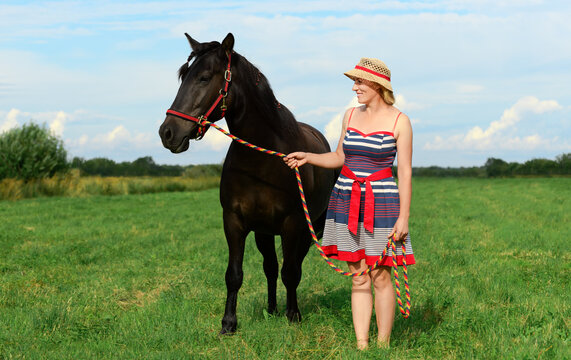 Caucasian woman, 40 years old, and her horse are standing in a field.