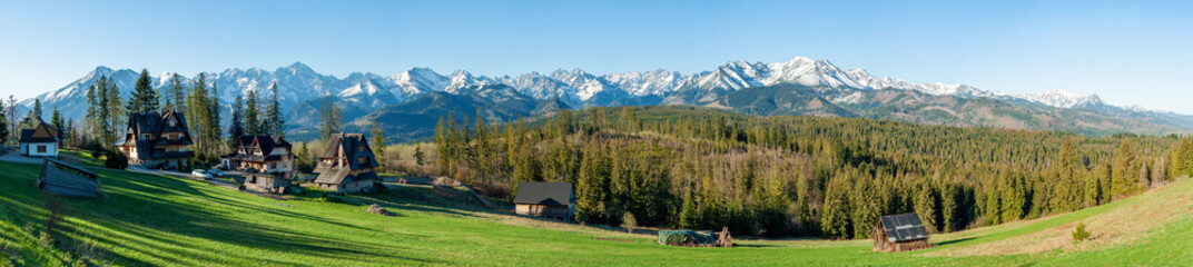 Full wide panorama of Tatra Mountains viewed from Głodówka glade in Poland with typical Polish highlander houses. Early morning in spring - obrazy, fototapety, plakaty