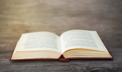 Open book lies on a gray wooden background close-up in sunbeams