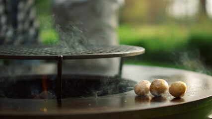 Male chef preparing potato on bbq grill outside. Man putting potato on grate