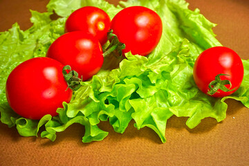 Red cherry tomatoes lie on a lettuce leaf.