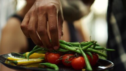 Chef hands putting vegan food on grill outside. Plate with grilled vegetables