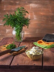 Cooking a light breakfast with pita bread and curd cheese, a bunch of dill