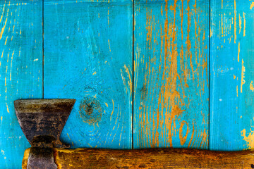 Rusty and old ax on old wooden table covered with blue paint. View from above