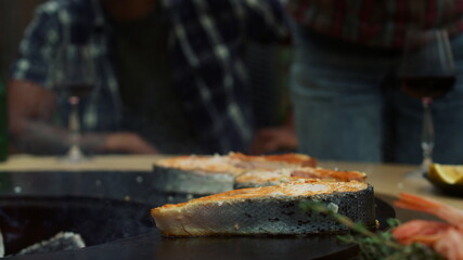 Woman chef salting fish on grill outside. unknown woman pouring salt on fish