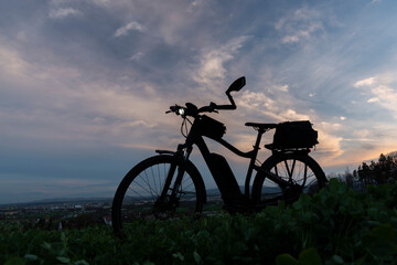 Fototapeta na wymiar Black and gray electric bicycle in sunset time with cloudy sky