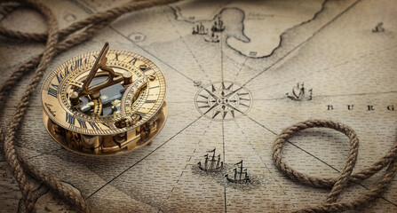 Fototapeta na wymiar Magnetic old compass and rope on vintage world map. Travel, geography, navigation, tourism and exploration concept wide background. Macro photo. Very shallow focus.