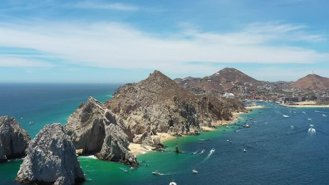 Aerial panoramic view of the tip of Peninsula de Baja California, in Cabo San Lucas, Mexico. Drone slowly descending with a blue sky as background.