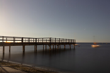 Fototapeta na wymiar Wooden jetty over the sea with silk effect on a starry summer night, Spain