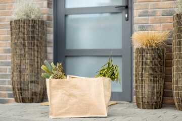 Shopping bag with fresh products from grocery on the doorstep at the front door of house. Contactless delivery concept.