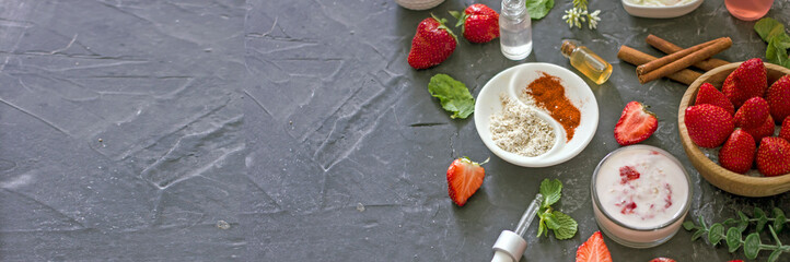 Ingredients homemade strawberry face mask, cream, strawberry, oatmeal, spices, herbs on a dark background, top view, copy space, flat lay, banner. Home hand-made cosmetics made from natural ingredient