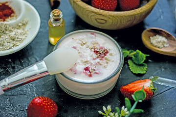 Homemade strawberry face mask with oatmeal and cream on a dark background. Concept of natural handmade cosmetics