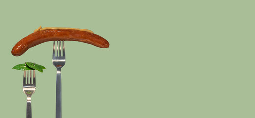 Banner with green fresh leaves picked by a fork for eating as new vegan food and grilled sausage with mustard on another fork at salad color solid background with copy space for text, closeup, details