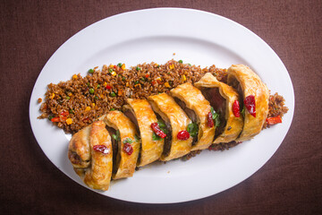 top view. baked roll with meat and rice on a white plate.