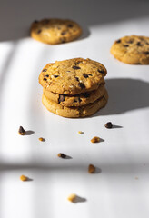 Chocolate chip cookies and crumbs on white background under the sunshine in front of the window