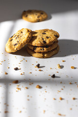 Chocolate chip cookies and crumbs on white background under the sunshine in front of the window