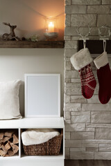 16x20 vertical Christmas and winter frame mockup. Cosy,  interior setting next to a fireplace and hanging Christmas stockings.