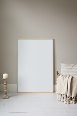 Thin wood frame poster mockup, resting on the floor and styled for fall or winter. Cosy props.