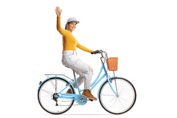 Full length profile shot of a young female riding a city bicycle and waving at camera