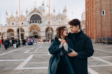 Fototapeta premium A love story in a town square with a boyfriend and girlfriend. Young people travel to Europe.