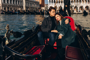 Fototapeta na wymiar A romantic ride for a guy and a girl on a gondola through the canals of Venice. A young couple travels to Italy.