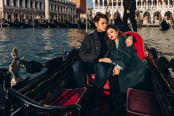 Fotobehang A romantic ride for a guy and a girl on a gondola through the canals of Venice. A young couple travels to Italy. © dimadasha