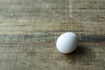 one white egg isolated on the wooden table in sunlight