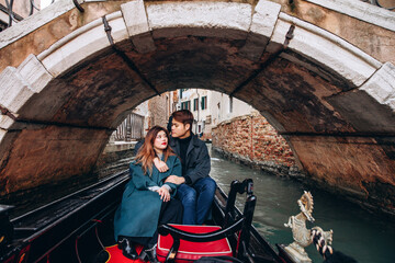 Obraz na płótnie Canvas A romantic ride for a guy and a girl on a gondola through the canals of Venice. A young couple travels to Italy.