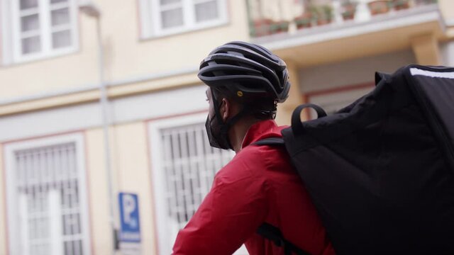 Young courier delivering a food on bike, looking for adress. Coronavirus concept.