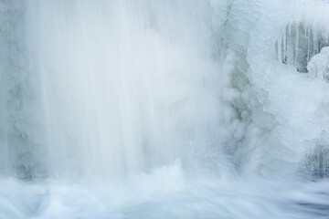 Winter landscape of a cascade captured with motion blur and framed by ice, Comstock Creek, Michigan, USA