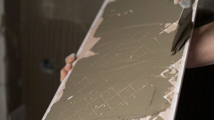 Laying ceramic tiles on the floor. Ceramic tile. The tiler is laying ceramic wall tiles on top of the adhesive. A worker smears ceramic tiles for laying.