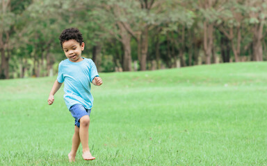 African mixed race adorable curly hair little boy running and playing in outdoor backyard, green field, park, garden with amusement and fun. There is copy space. Education, Kid and Diversity Concept.