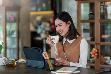 Young Asian woman leisure time enjoying the pleasure of drinking coffee and at tablet the café.