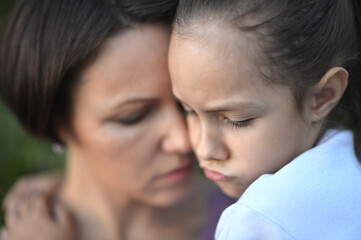 Close up portrait of sad woman and girl hugging