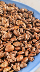 Selected focus composition with roasted coffee beans on a blue plate, close up. Vertical banner for coffee shops