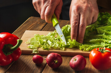 Cooking salad in the restaurant kitchen. Chef is hands close-up cut salad greens. Set of vegetables for a salad diet