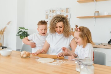 happy family in the kitchen. mother and children preparing the dough, bake cookies