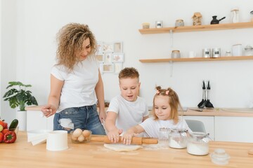 Family learning new recipe together. Happy mom and kids mixing ingredients for homemade cake, pie or cookie dough in the kitchen.