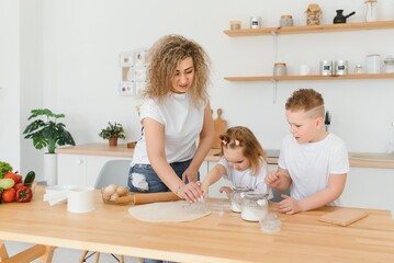 Family learning new recipe together. Happy mom and kids mixing ingredients for homemade cake, pie or cookie dough in the kitchen.