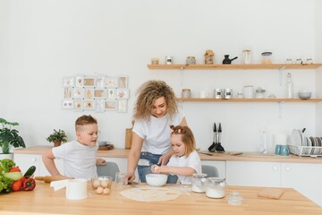 Family learning new recipe together. Happy mom and kids mixing ingredients for homemade cake, pie or cookie dough in the kitchen.