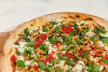 Ricotta Cheese Pizza with Basil and Nuts on a Rustic Tomato Sauce Homemade Artesanale Close Up Detail on a Round Wooden Plate with Flour Background Table
