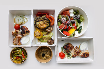 Food delivery in cardboard bowls.Proper nutrition separately. portions.Grilled vegetables with barbecue and salad.Food delivery for lunch.Greek salad in a bowl.Take-out banquet.Meat with asparagus.