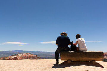 Pareja sentada en banco observando el paisaje desértico.