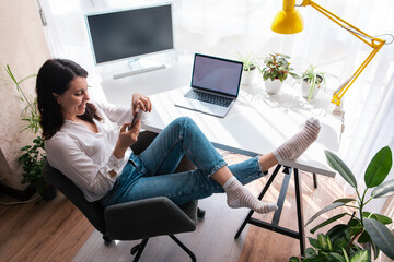 woman freelancer sitting at working place surfing internet on the phone
