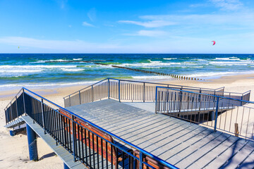 Entrance to beautiful beach in Grzybowo village near Kolobrzeg town and surfing kites on blue sky, Baltic Sea coast, Poland