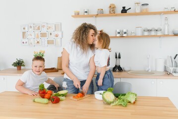 Young mother and her two kids making vegetable salad