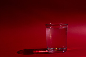 Glass of water with red background