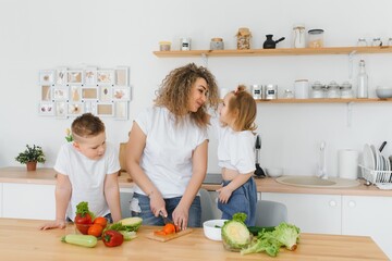 mother with children preparing vegetable salad at home