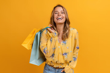 beautiful attractive smiling woman in yellow shirt and jeans holding shopping bags