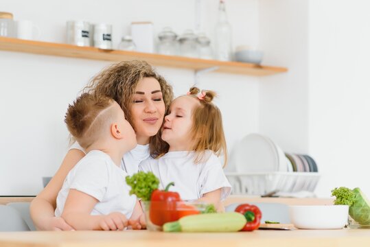 Young Mother And Her Two Kids Making Vegetable Salad